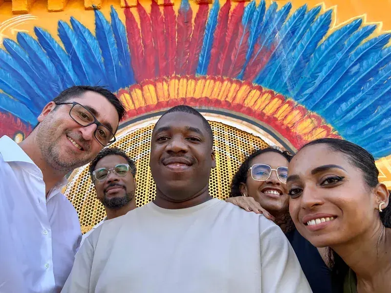 Selfie de cinq collègues devant une fresque de coiffe à plumes rouge et bleu